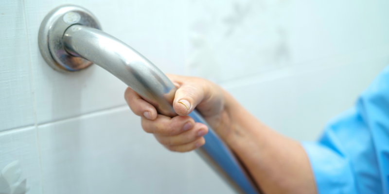 A Woman Holds a Grab Bar Rail for Stability. Medical Equipment Like Grab Bars Can Promote Safety, Accessibility, and Independence.