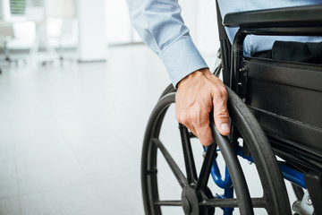 closeup of a man with his hand on a wheelchair wheel