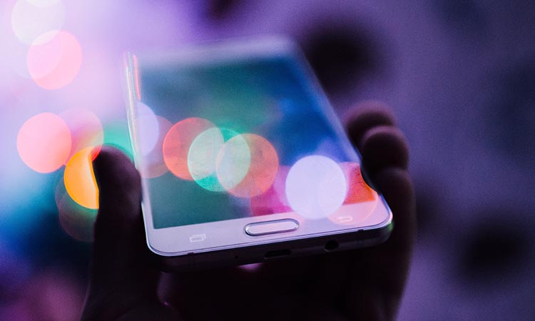 hand holding a smart phone with blurred lighting effects