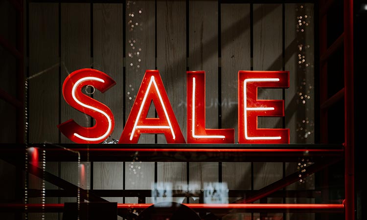 red neon SALE sign in a commercial storefront window at night