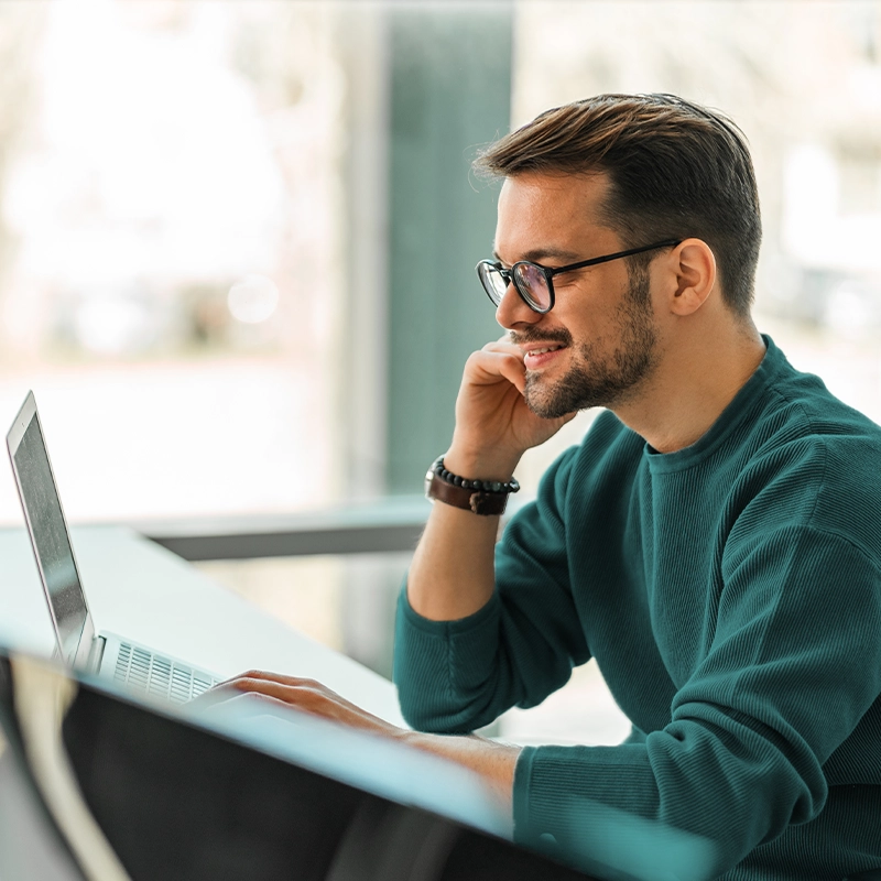 image of young msn smiling working on laptop computer at office