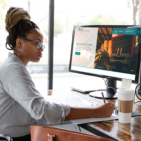 A woman working at her desk with a computer monitor and coffee cup resting on the desk